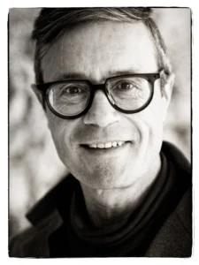 Portrait of Lode Laperre, smiling, wearing round black glasses.