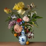 Yellow iris, tulips, a pale rose, lily of the valley and a ranunculus in a Delft blue bottle vase, with two orange tomatoes on the ledge and a swallowtail butterfly.