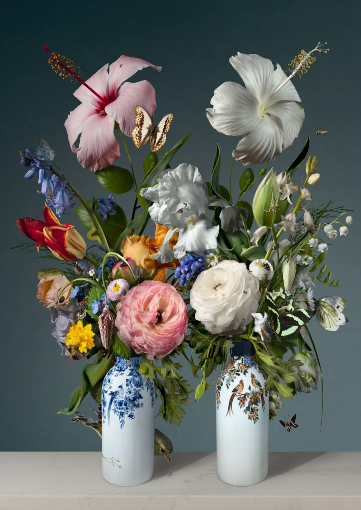 Pink and white hibiscus, roses and tulips in two white Delft vases side by side.