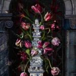 Tulips in a Delft blue flower pyramid set in a dark stone niche.