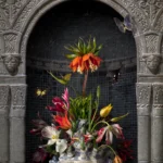 A Delft blue flower pyramid filled with tulips and a crown imperial in a carved stone niche.
