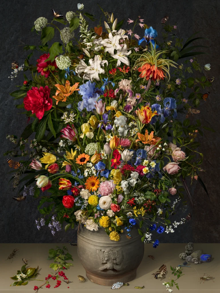 A dense bouquet of lilies, roses, cornflowers and tulips in a grey stoneware pot, with fallen petals and a beetle on the ledge.
