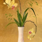 A single orchid stem with grasses in a slender white vase against a gold-leaf ground, with a piece of rose quartz on the ledge.
