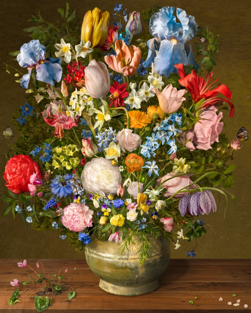 A dense bouquet of iris, tulips, peonies and roses in a stoneware pot on a wooden ledge against a gold ground, with fallen petals.