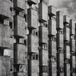 Façade of an apartment block with staggered rectangular concrete balconies in offset rows, seen from below.