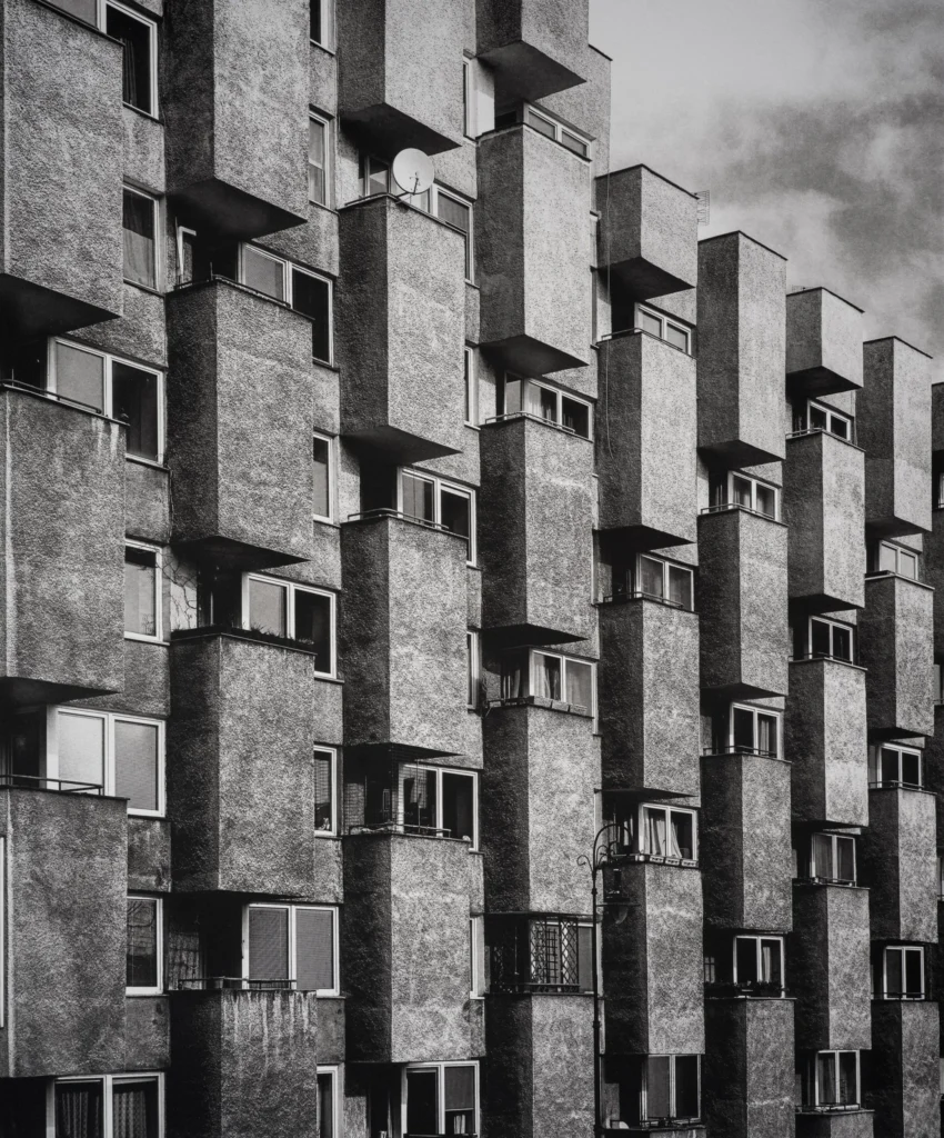 Façade of an apartment block with staggered rectangular concrete balconies in offset rows, seen from below.