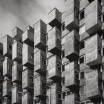 Tower façade of cantilevered concrete boxes projecting at alternating angles, seen from below.