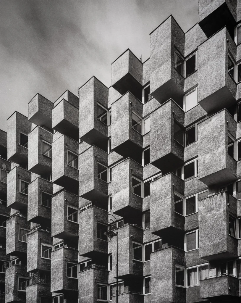 Tower façade of cantilevered concrete boxes projecting at alternating angles, seen from below.