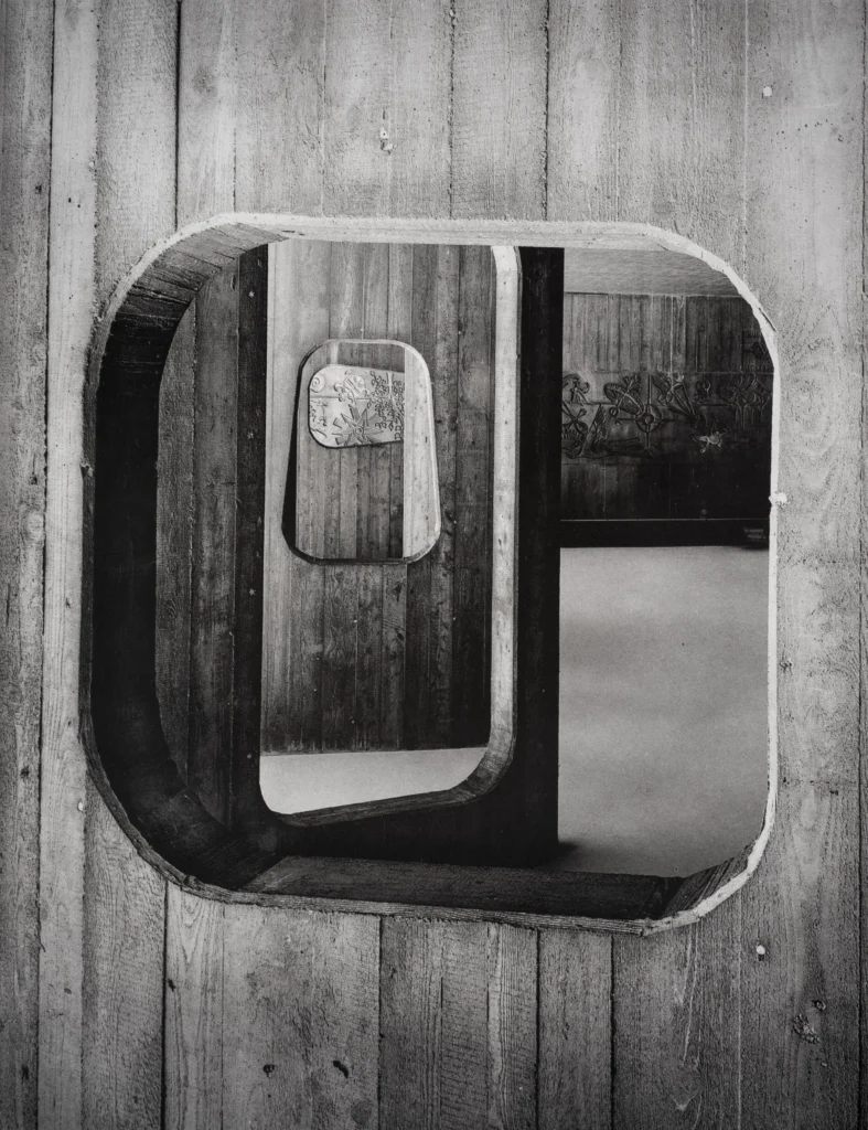 Close view of a rounded rectangular concrete window set into a striped concrete wall, framing a second rounded window inside it.